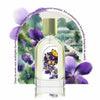 A perfume bottle with a floral design sits in front of an illustrated garden scene adorned with flowers and French text above. The Eau de Parfum, Violette Kew by Le Jardin Retrouvé, is a unisex fragrance that captures the essence of blooming gardens.