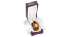 A bottle of Xerjoff Alexandria II Anniversary perfume in brown glass with a golden cap is displayed in an open purple box lined with branded white paper.