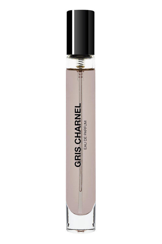 A clear cylindrical glass bottle with a black cap contains Gris Charnel by BDK Parfums Eau de Parfum, reminiscent of an evening stroll in the Tino-Rossi garden. The bottle has the product name and type printed vertically in black letters.