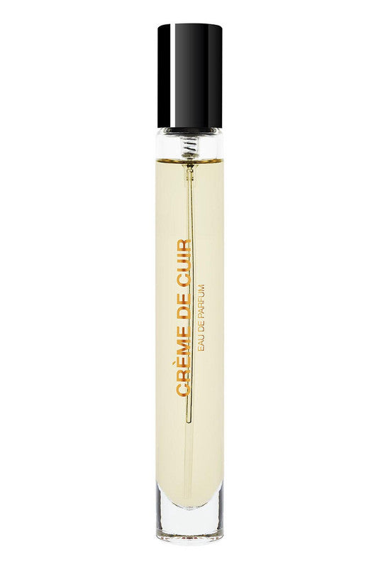 A clear glass perfume bottle with a black cap, filled with light yellow liquid, bears the label "CRÈME DE CUIR EAU DE PARFUM." This exquisite fragrance by BDK Parfums exudes contemporary sensuality through the essence of white suede.