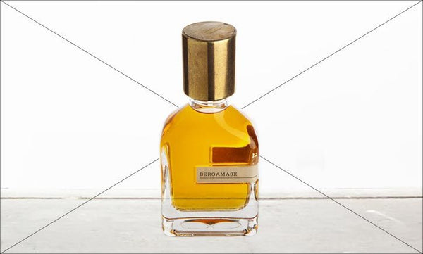 A glass bottle with a gold cap containing a golden liquid labeled "BERGAMASK" from Orto Parisi rests on a white surface against a white background. Crafted by Alessandro Gualtieri, this Citrus Aromatic fragrance exudes elegance and sophistication.