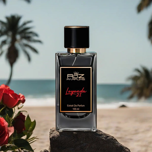 A bottle of Leyenda 21 perfume by RDZ Parfums stands on a rock at the beach, exuding its luxurious scent. Red roses are on the left, and palm trees with an ocean view are in the background, capturing a moment as timeless as Roberto Clemente’s legacy.