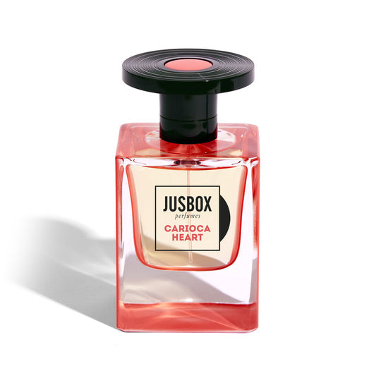 A bottle of Jusbox "Carioca Heart" perfume. The rectangular bottle, designed by Julien Rasquinet, features pink accents and a black cap, evoking the vibrant spirit of Bossa Nova.