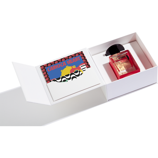 A white rectangular box containing a bottle of Jusbox Carioca Heart perfume with a fruity, woody, musky aroma and a colorful card inside a sleeve.