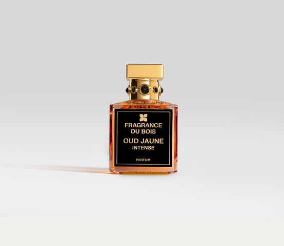 A square bottle of Oud Jaune Intense by Fragrance Du Bois, adorned with a black and gold design, placed on a plain white background, captures the essence of an exotic monoi scent.