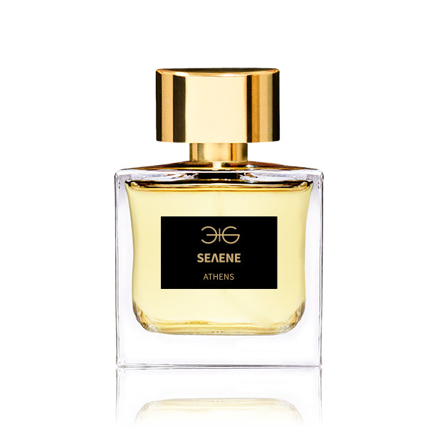 A clear glass perfume bottle with a gold cap and a black label reading "Selene Manos Gerakinis," containing a yellow liquid reminiscent of night-blooming jasmine, evokes the essence of an Athenian summer night.