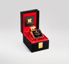 A square perfume bottle with a gold cap, labeled "Oud Jaune Intense" by Fragrance Du Bois, is displayed upright in a black and red velvet-lined box. The box lid is open, revealing gold text inside and evoking the luxurious allure of this oriental floral fragrance enriched with exotic monoi.