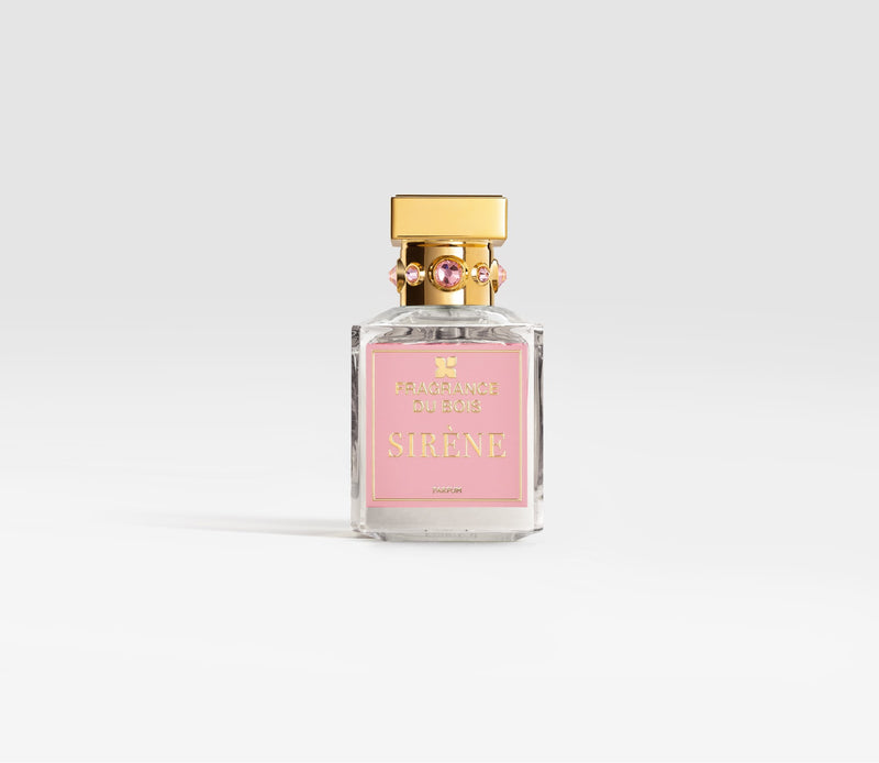 A bottle of Fragrance Du Bois SIRÈNE, with a gold cap and a pink label, sits elegantly against a plain background, exuding a seductive burst of cherries perfect for the female-inspired fragrance.