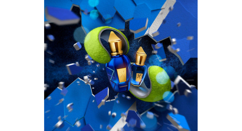 Two perfume bottles bursting out of a tennis ball with a blue background