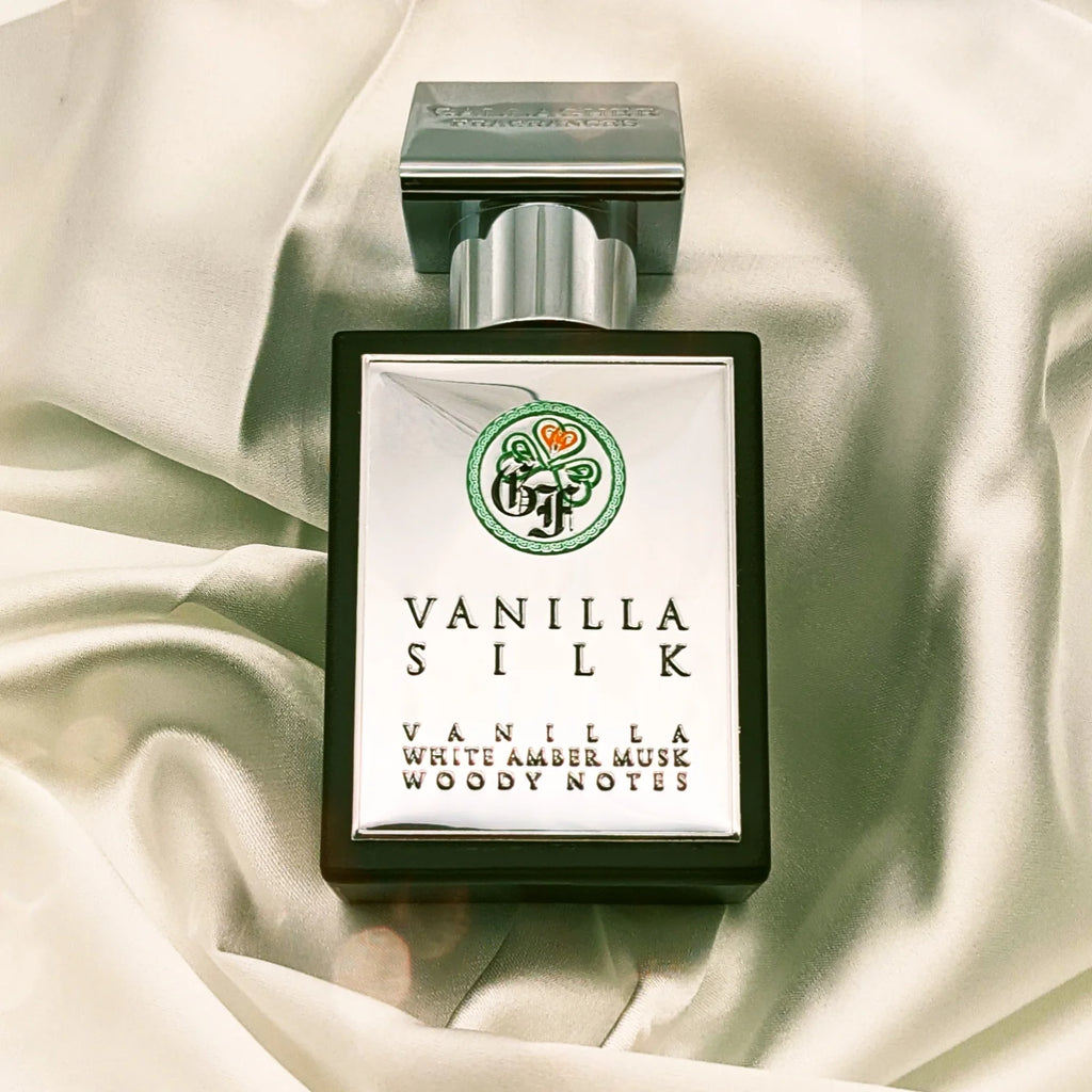 A perfume bottle of Vanilla Silk by Gallagher Fragrances, featuring notes of amber vanilla, white amber musk, and woody undertones, gracefully placed on a satin fabric background.