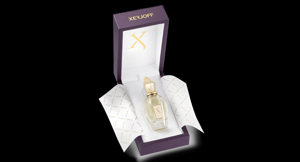 A bottle of Via Cavour 1 perfume from Xerjoff is displayed inside an open purple and white box with gold accents, exuding a sense of sophistication.
