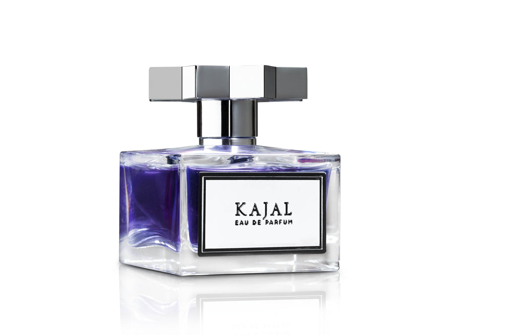 A clear glass bottle of Kajal from the Kajal - Classic Collection with a silver cap and a white label on the front, standing against a white background. This exquisite fragrance features top notes that capture the essence of elegance and sophistication.
