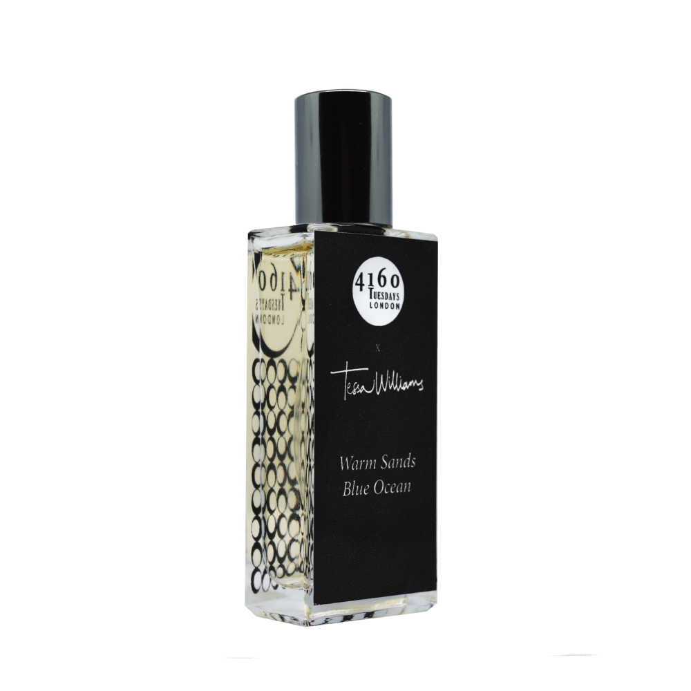 A rectangular perfume bottle labeled "4160Tuesdays" and "Warm Sands, Blue Ocean" with a black cap and black label adorned with white text and patterns, evoking the essence of seaside fragrances.