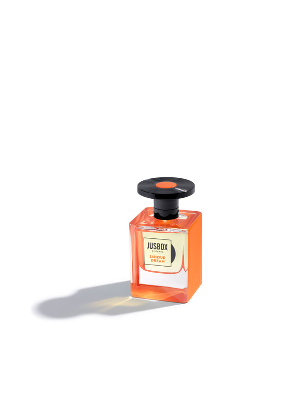 An orange glass bottle of Jusbox 14Hour Dream perfume with a black cap, casting a shadow on a white background, reminiscent of the vibrant energy of Pink Floyd's psychedelic rock and the legendary 14 Hour Technicolor Dream.
