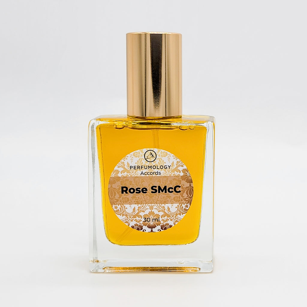 A square glass perfume bottle with a gold cap contains yellow liquid and has a label that reads "Perfumology Accords Rose SMcC 30ml." Crafted by Sarah McCartney of 4160 Tuesdays, this perfect rose scent captures elegance in every drop.