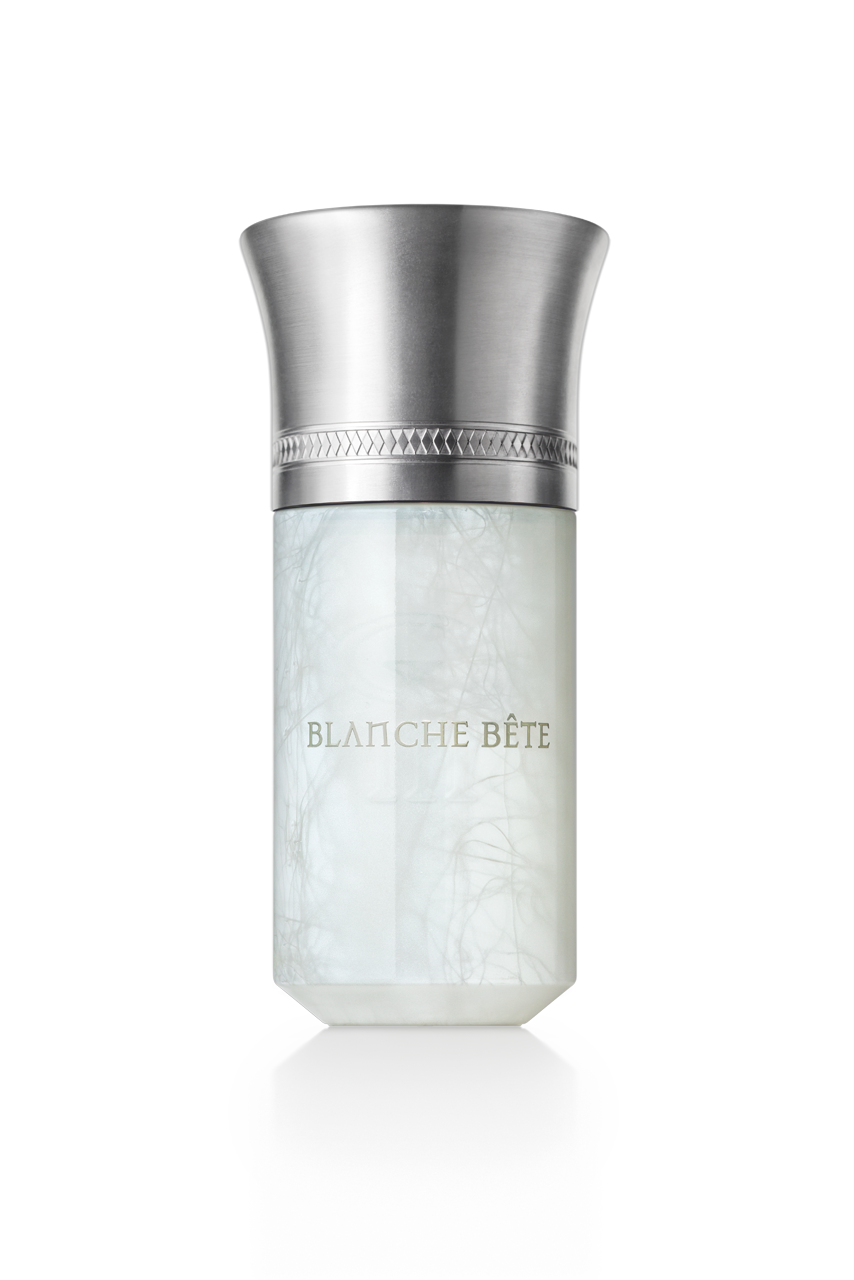 A cylindrical perfume bottle with a metallic cap and a frosted white body, labeled "Blanche Bete" by Liquides Imaginaires in gold lettering—like the essence of a mythical creature captured within.