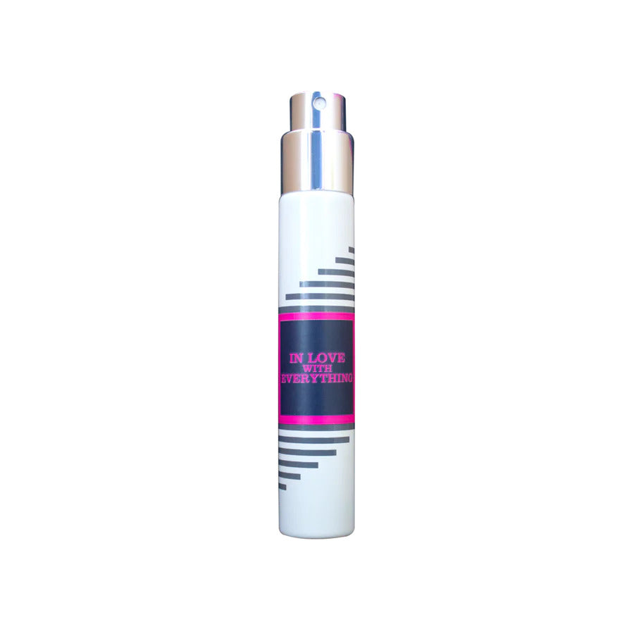 White cylindrical spray bottle by Imaginary Authors with a silver top and black stripes. The label reads "In Love with Everything" in pink text, evoking a hint of decadence.