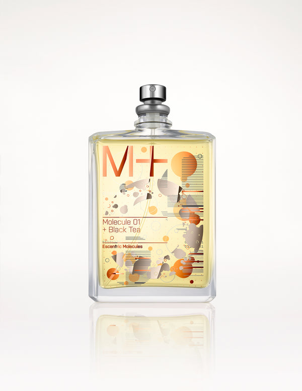 A bottle of Molecule 01 + Black Tea by Escentric Molecules sits on a white background. The clear bottle showcases a label adorned with abstract designs and text in orange and black, emphasizing the Iso E Super essence that blends effortlessly with the rich scent of black tea.