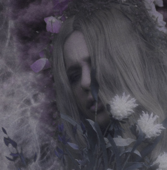 A person with long hair partially obscured by flowers and foliage, surrounded by a dark, abstract background reminiscent of Ikiryo's Annwyn.