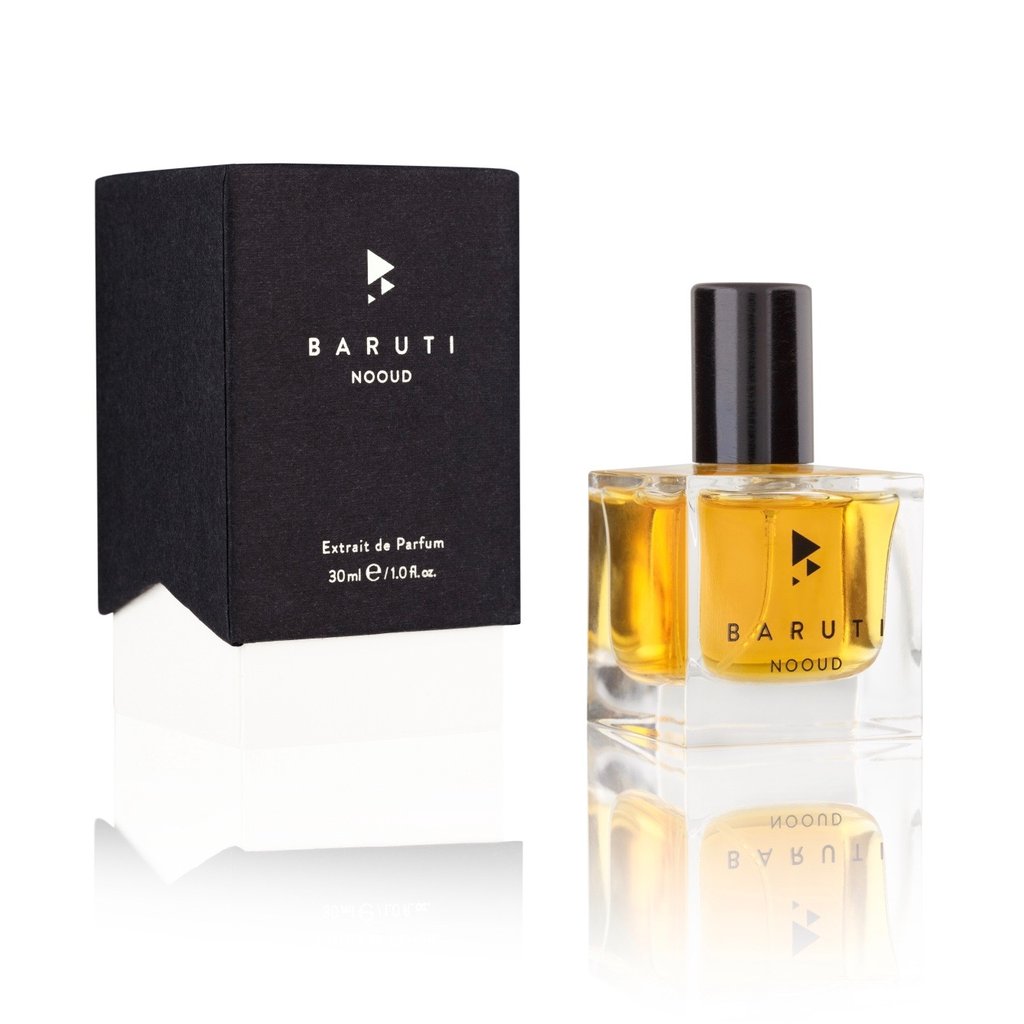 A 30ml bottle of Baruti Nooud Extrait de Parfum, a captivating dark woody fragrance housed in a transparent glass container with black label and cap, sits next to its sleek black packaging box.