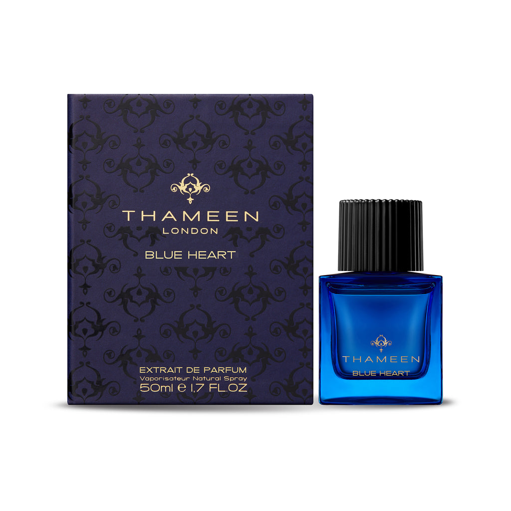 A blue bottle of THAMEEN Blue Heart is placed next to its matching blue box. The box, adorned with ornate designs and elegant text, details the perfume’s size and type. Inspired by the legendary Blue Heart Diamond, this fragrance has subtle hints of vanilla intertwined within its luxurious scent.