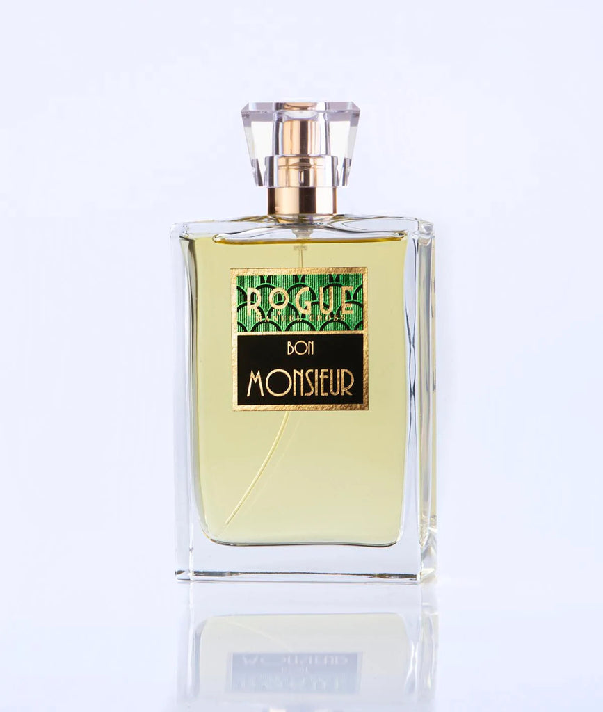 A bottle of Bon Monsieur perfume by Rogue Perfumery, a quintessential Gentlemen's fragrance, featuring a clear rectangular design with a gold and green label and a transparent square cap, set against a plain white background.