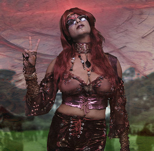 A red-haired individual in sunglasses, outfitted in a colorful, artistic costume and flashing a peace sign against a surreal backdrop, perfectly embodies the unisex patchouli-infused vibe of Ikiryo’s Damn Hippie.