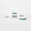 Three product packages are displayed against a plain background: a small rectangular box, a cylindrical container, and a larger rectangular box, all capturing the classic simplicity reminiscent of Aida Overton Walker's vaudeville performances. These products are part of the DREAMER in London collection by Nomad Noe.