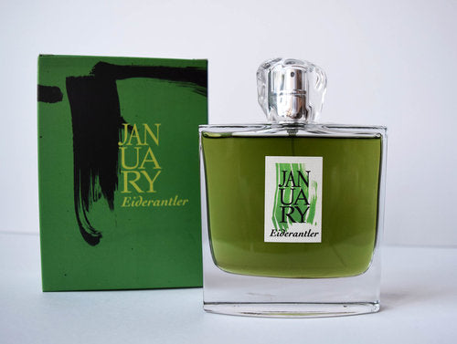 A glass bottle of green perfume labeled "Eiderantler" by January Scent Project rests beside its matching green box, both exuding the essence of an Ivy Fougère Eau de Parfum.