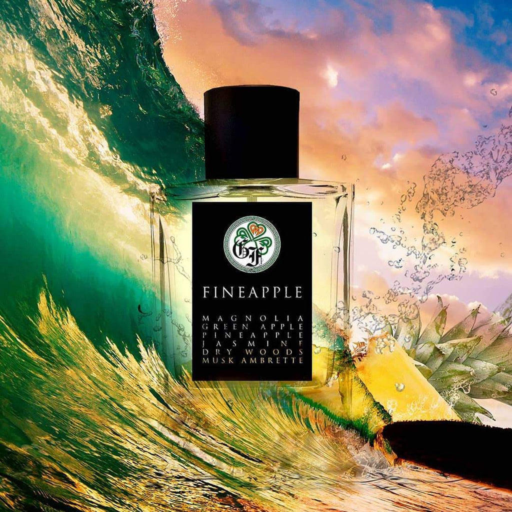 A bottle of Gallagher Fragrances' Fineapple perfume, prominently displaying ingredients such as Magnolia on the label, is set against a vibrant scene with a pineapple and dynamic water splashes.