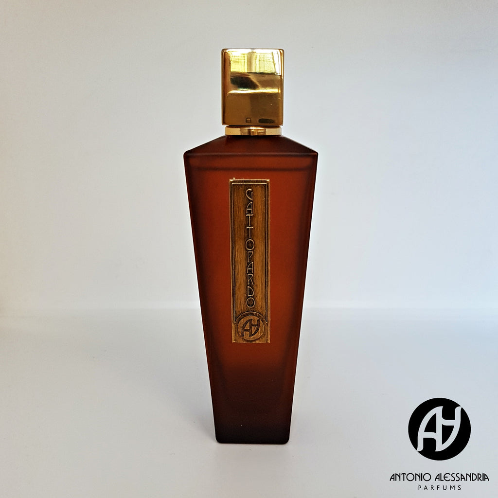 A brown, rectangular perfume bottle with a gold cap and label, displaying "Gattopardo" by Antonio Alessandria, exudes a gourmand essence. The brand's logo, a stylized "AA," is visible at the bottom right of the image.