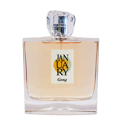 A transparent, square perfume bottle filled with an amber liquid is adorned with a minimalist label that reads "January Scent Project - Gong Eau de Parfum," hinting at notes of Fruit and Green Musk.