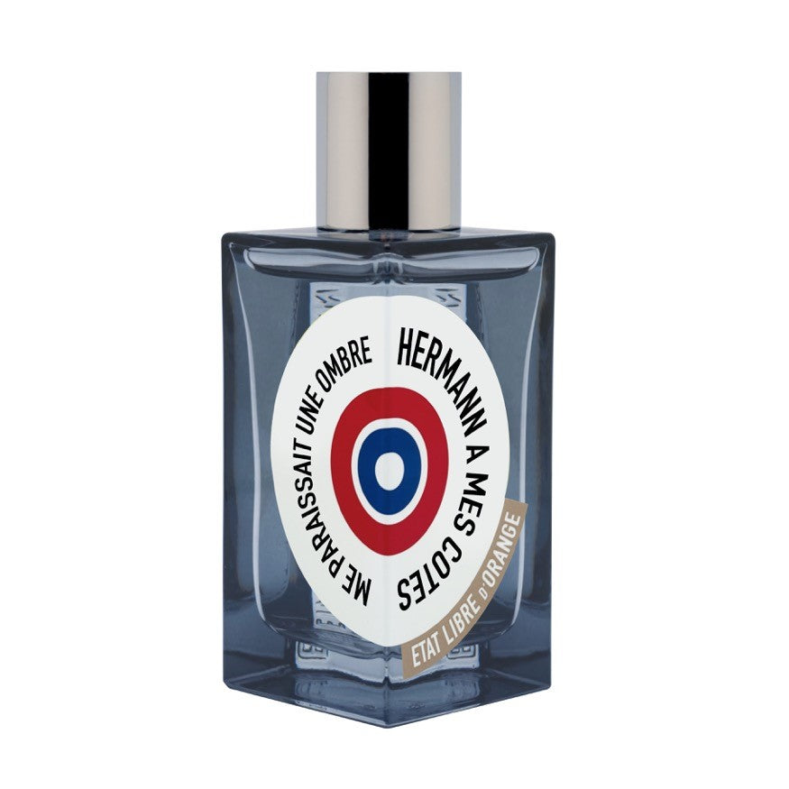 Bottle of Hermann A Mes Cotes perfume by État Libre d'Orange, featuring a dark square design and a circular label on the front, exuding a sheer and woody fragrance that speaks to your alternative self.