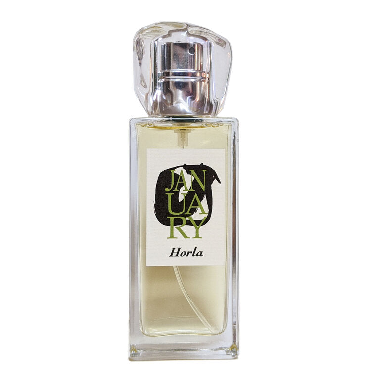 A clear perfume bottle labeled "Horla" and "January Scent Project," featuring a metallic spray nozzle, showcases the exquisite blend by John Biebel.