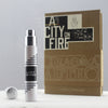 An Imaginary Authors A City On Fire unisex perfume bottle with cap off, positioned in front of its brown and black packaging box. The refined smoke accord wafts delicately, blending seamlessly with the elegant white table surface and muted gray backdrop.