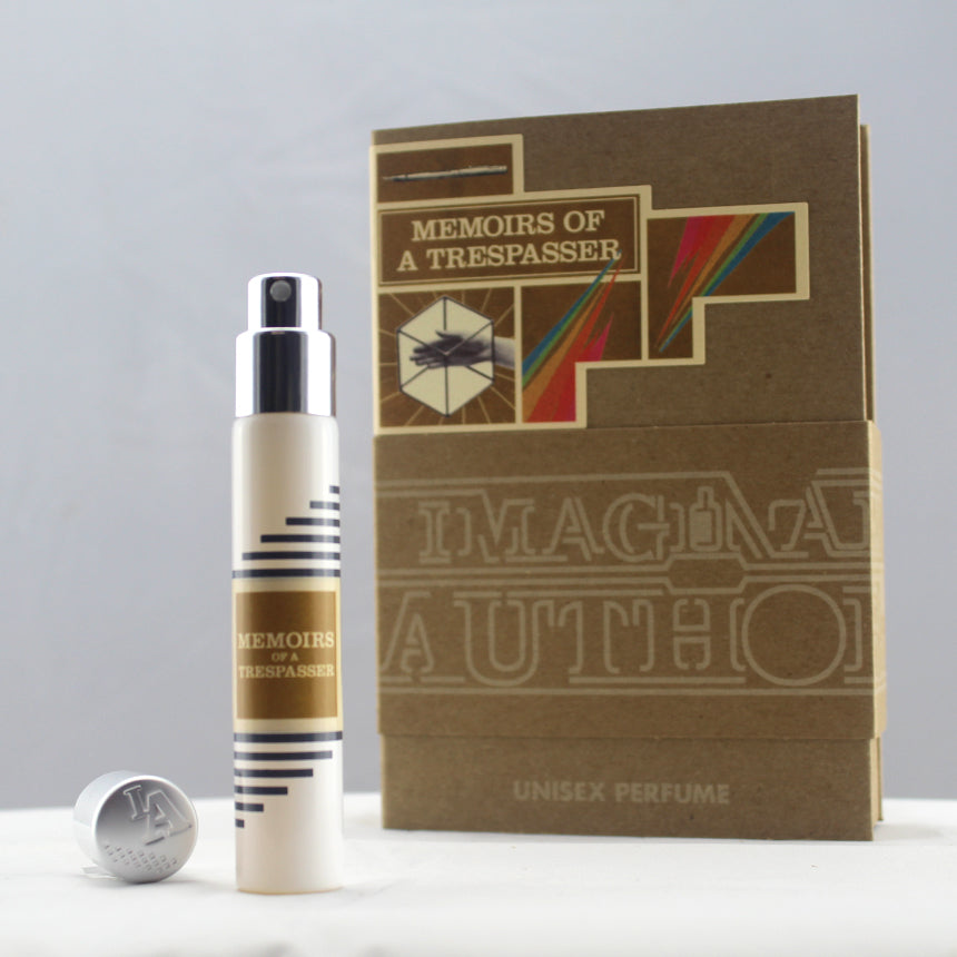 A spray bottle of "Memoirs of a Trespasser" by Imaginary Authors is displayed in front of its packaging box, which features a vintage design with text and geometric patterns, subtly hinting at the rich notes of Madagascar Vanilla within.