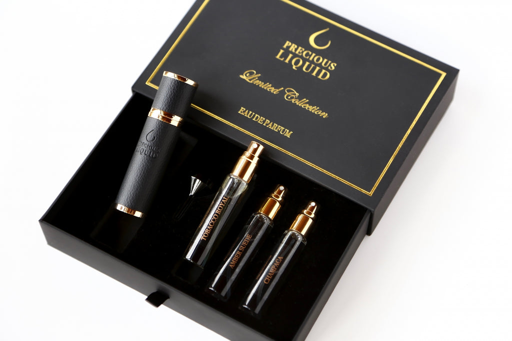A box labeled "Precious Liquid Limited Collection Discovery Travel Set" containing one large bottle, three smaller spray bottles, and a small funnel, featuring the enchanting scent of Oud Symphony.