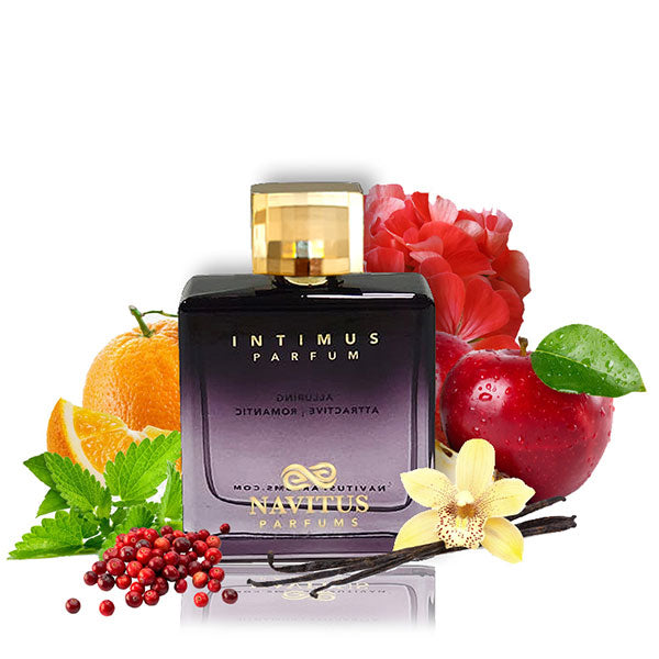 A bottle of Intimus by Navitus Parfums, a romantic fragrance, is surrounded by oranges, an apple, a red flower, mint leaves, red peppercorns, patchouli leaves, a vanilla flower, and vanilla pods.