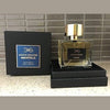 A bottle of Manos Gerakinis Immortelle with a gold cap is displayed next to its black box, which features intricate gold and blue detailing, celebrating Greek heritage.