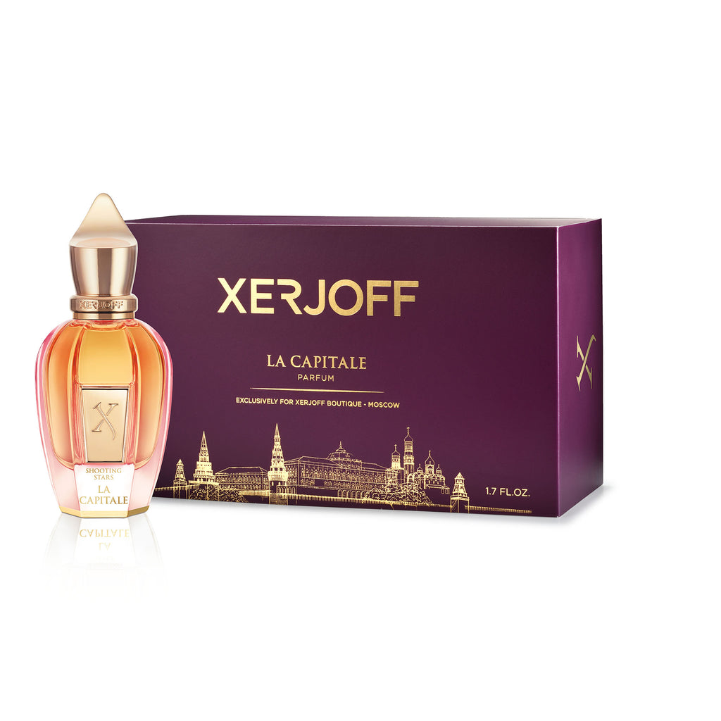 The La Capitale perfume bottle from Xerjoff, embodying modern romanticism, sits elegantly next to its maroon box. The bottle's gold cap complements the golden text and intricate illustrations that adorn the box, reflecting a touch of Russian art with the perfume's name and details prominently displayed.