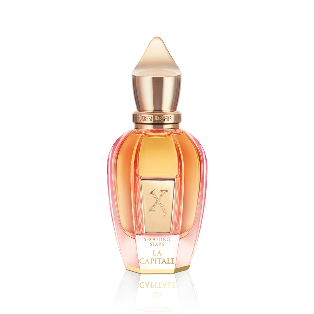 A bottle of La Capitale perfume by Xerjoff, from the Shooting Stars collection, inspired by Moscow's modern romanticism, featuring a gold cap and gradient pink to amber glass design.