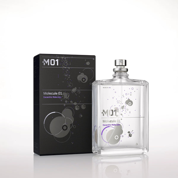 Image of Escentric Molecules' Molecule 01 fragrance bottle and its packaging. The transparent bottle with minimalistic design elements holds the signature Iso E Super scent, while the sleek black packaging features similar graphics.