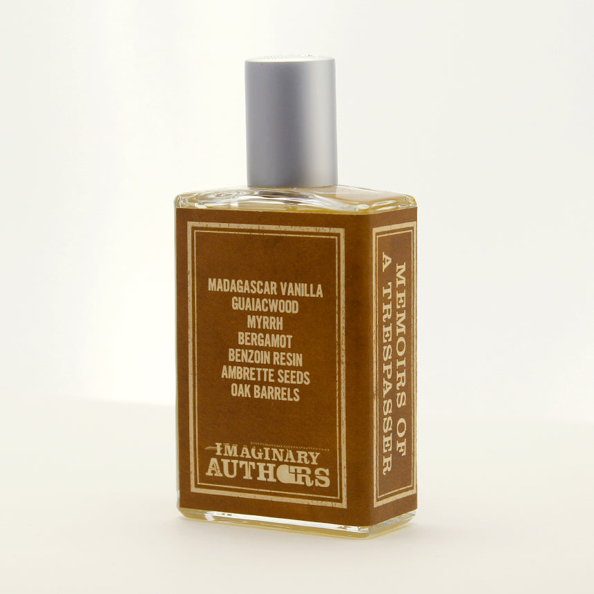 A bottle of "Memoirs of a Trespasser" perfume by Imaginary Authors features a label listing ingredients like Madagascar vanilla, guaiacwood, myrrh, and bergamot. This adventurous fragrance captures the essence of far-flung escapades and mysterious allure.