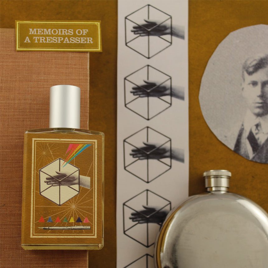 A bottle labeled "Memoirs of a Trespasser" from Imaginary Authors, accompanied by graphic art, a silver flask, a cut-out photo of a man, and a book with the same title arranged on a brown surface. The arrangement exudes an adventure scent with notes of Madagascar Vanilla, while a photo strip enhances the nostalgic charm.