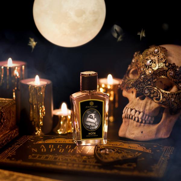 A bottle of perfume labeled "Moth" by Zoologist and known for its gothic scent is set among lit candles, a masquerade mask on a skull, and a book with letters by moonlight.