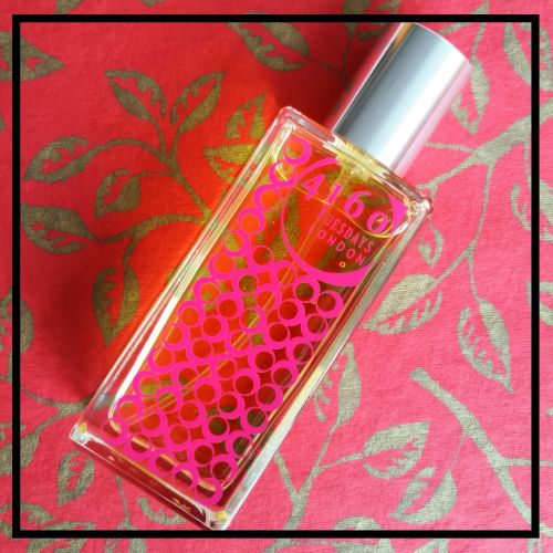 A clear bottle of 4160Tuesdays' Mother Nature's Naughty Daughters perfume with a pink circle design on a red and gold patterned background, featuring the rich notes of Opoponax.