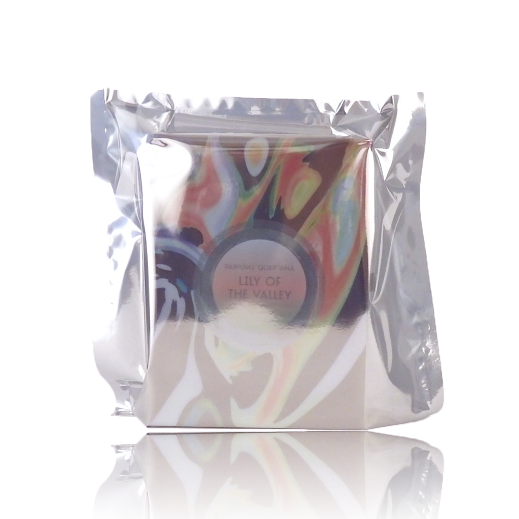 A reflective, silver, vacuum-sealed packaging with a label reading "Lily of the Valley by Parfums Quartana" and abstract colorful artwork.