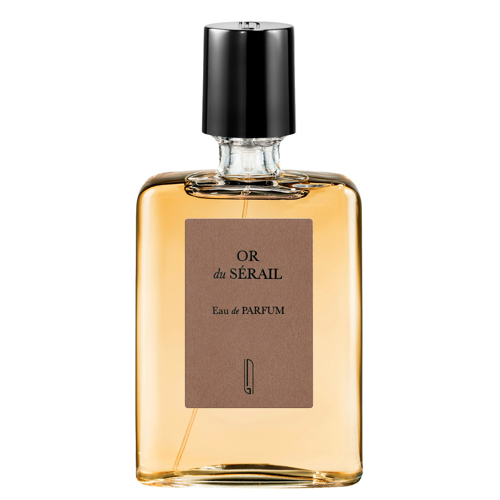 A clear glass bottle of OR du SÉRAIL Eau de Parfum by Naomi Goodsir, created by Bertrand Duchaufour, featuring a black cap and a brown label with the product's name and details. This oriental perfume captures the essence of golden tobacco.
