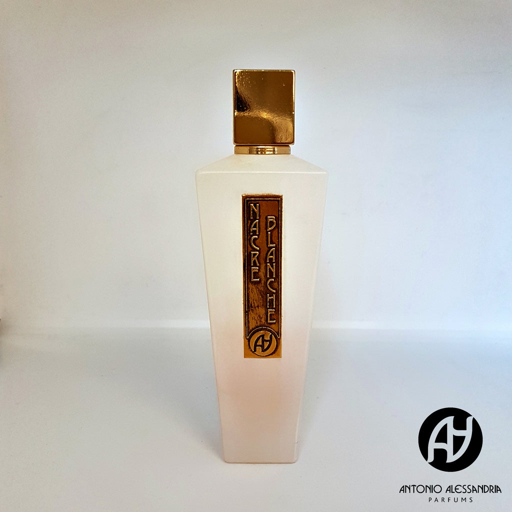 A white, angular perfume bottle with a gold cap and a gold label reading "Nacre Blanche" by Antonio Alessandria. The "Antonio Alessandria Parfums" logo is positioned at the bottom right corner, containing an exquisite floral fragrance with notes of tuberose.