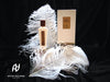 A white perfume bottle and its matching box labeled "Nacre Blanche" are placed on white feathers, exuding an enticing floral fragrance. The Antonio Alessandria logo is visible in the corner on a black background.